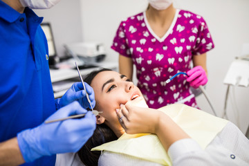 Young woman patient at dentist, holding hand on cheek, showing pain in dental clinic