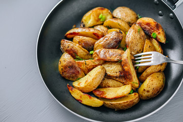 Baked potatoes in a pan on a gray background close up