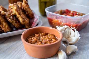 Breaded soya chunks, homemade pickled paprika with garlic, pickled cucumber, garlic cloves and sauce on wooden table