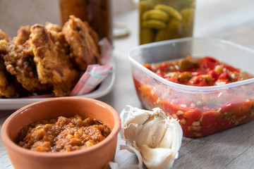 Breaded soya chunks, homemade pickled paprika with garlic, pickled cucumber, garlic cloves and sauce on wooden table
