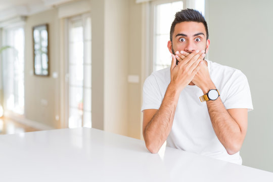 Handsome hispanic man casual white t-shirt at home shocked covering mouth with hands for mistake. Secret concept.