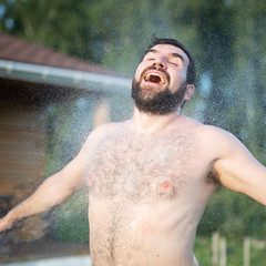 Hairy man in the water spray