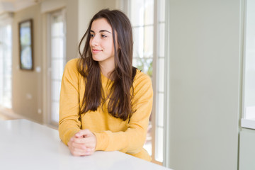 Beautiful young woman wearing yellow sweater looking away to side with smile on face, natural expression. Laughing confident.