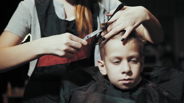 Close-up of a hairdresser doing a hair-dressing machine for a boy. Haircut of a children's hair trimmer and comb at the hairdresser.