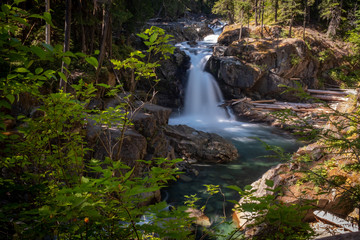 The Ohanapecosh River cascades Silver Falls at Mount Rainier National Park, a wide view framed by foliage