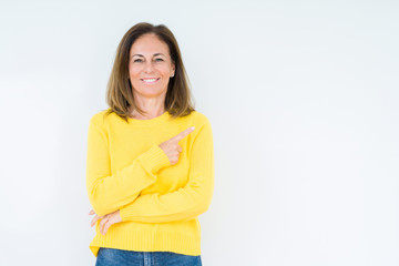 Beautiful middle age woman wearing yellow sweater over isolated background cheerful with a smile of face pointing with hand and finger up to the side with happy and natural expression on face