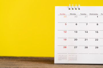 close up of calendar on the table with yellow background, planning for business meeting or travel planning concept