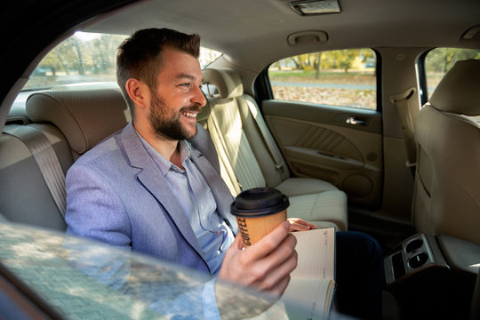 Man Drinking Coffee On The Back Seat Of The Car