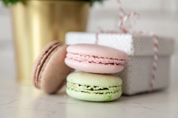 Macaron cookies, gift boxes and flowers on white wall background
