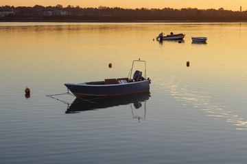 Three small boats in the river with sunset colors