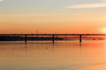 Fototapeta na wymiar Bridge over the calm river with sunset colors. 