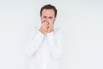 Elegant senior man over isolated background smelling something stinky and disgusting, intolerable...