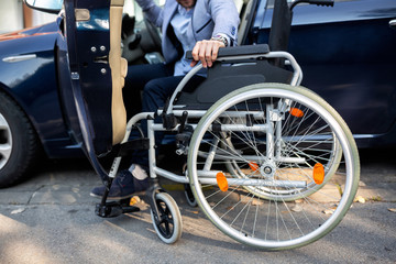 Fototapeta na wymiar Young handicapped man reaching for his wheelchair