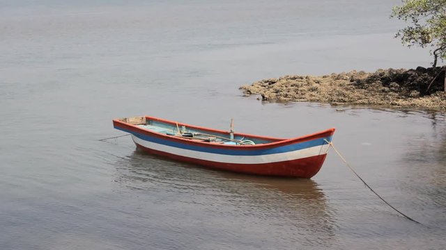 empty colored wooden fishing boat anchored off the coast