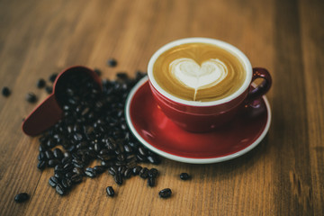 Heart latte art with coffee beans on wooden table