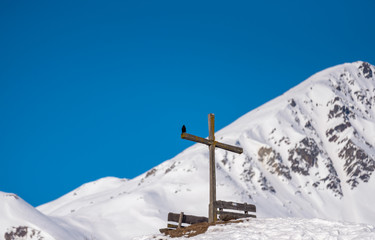 Fototapeta premium a cross between two benches at the top of a hill in winter.