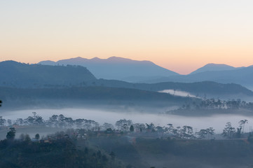Fog cover small village at the foot mountains with the magical of light at dawn