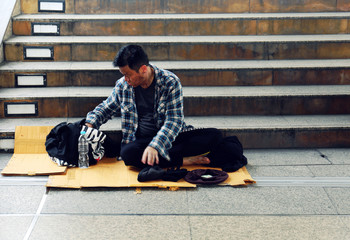 Close-up homeless man sitting on walking street in the capital city.