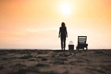 Obraz premium Woman standing near sun lounger and taking a picture on the mobile phone. Beach at sunset. Summer concept.