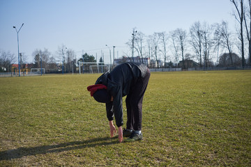 chłopak ćwiczy, robi skłon na stadionie © ftomasz