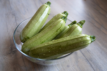 Light green zucchini in a glass bowl on white wooden table