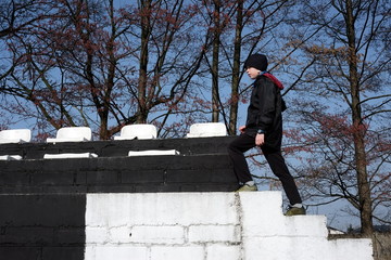 chłopiec w czarnej kurtce wchodzi bo białych schodach na mur  © ftomasz