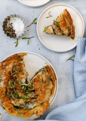 Greek pie spanakopita on light blue background. Ideas and recipes for vegetarian or vegan Spinach Pie from fillo pastry cut in slices. Copy space. Top view or flat lay.