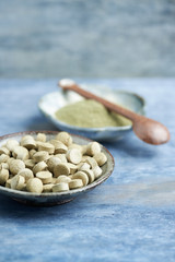 Bio Green BARLEY GRASS tablets and powder. Concept for a healthy dietary supplementation. Rustic wooden background. Copy space. 