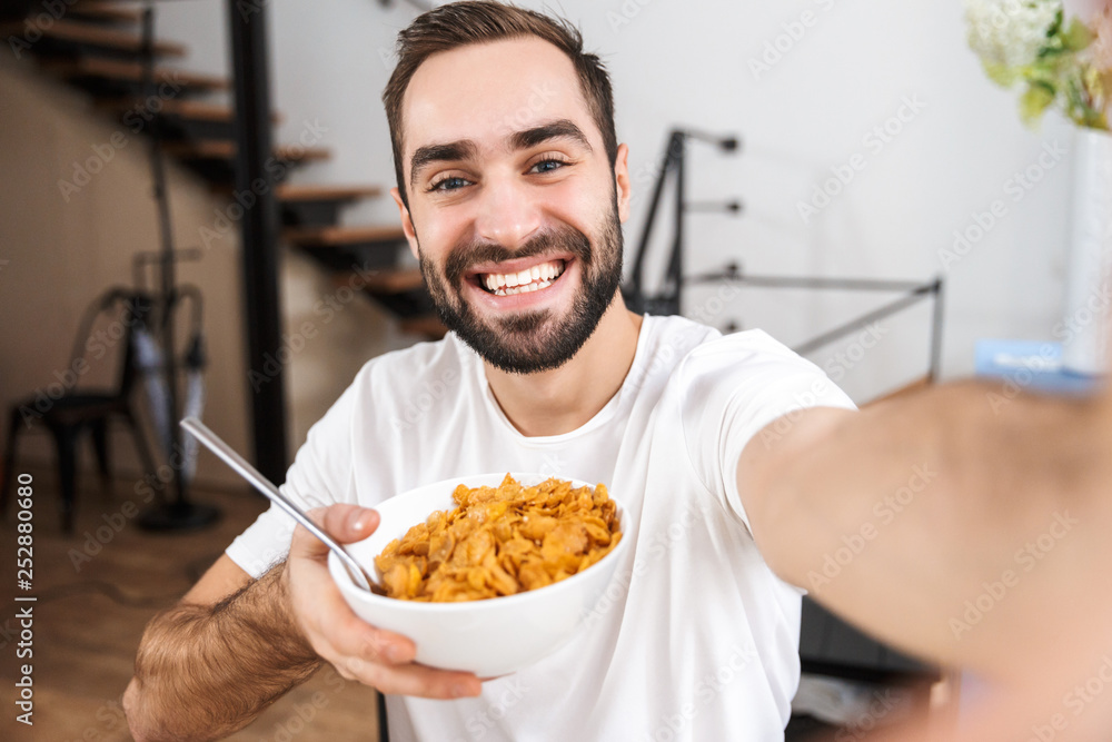 Wall mural Happy man taking a selfie while sitting at the kitchen