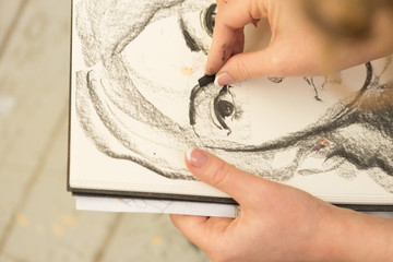 Young girl doing a sketch of natural charcoal on paper