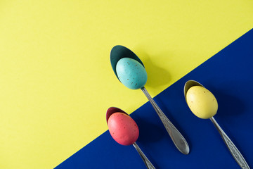 The eggs in pastel primary colors on spoons before Easter events in the springtime 