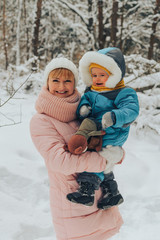 Mom walks with the child in the winter in nature. Family walks in nature in winter. Winter forest. Snow park.