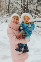 Mom walks with the child in the winter in nature. Family walks in nature in winter. Winter forest. Snow park.