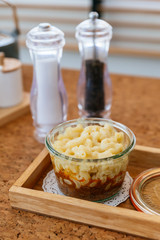 Macaroni Cheese Baked with meat sauce in glass bowl on wooden plate with salt, pepper and cutlery.