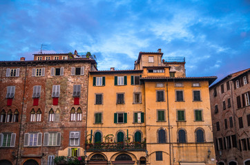 Fototapeta na wymiar Typical traditional italian buildings on Piazza San Michele square in historical centre of old medieval town Lucca, evening view, Tuscany, Italy