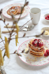 Breakfast table with pancakes through the branches of pussy-willows and birch blooms