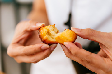 Female hands tearing fresh baked Canelés, A small French pastry flavored with rum and vanilla with...