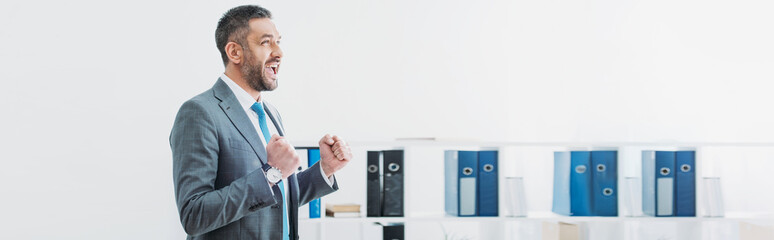 handsome businessman standing and showing yes gesture in office