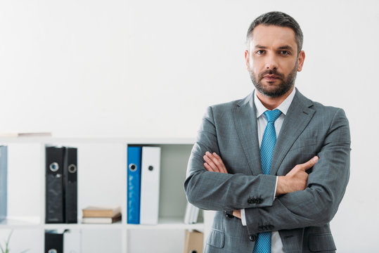 handsome businessman standing with crossed arms in office