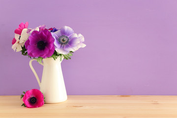 spring bouquet of colorful anemones in the vase over wooden table