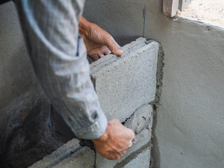 professional construction worker laying bricks with cement.