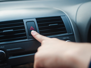 Driver's finger pressing car's emergency button in the car