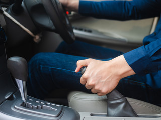 driver's hand pulling the hand brake in a car