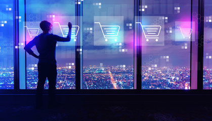 Fototapeta na wymiar Online shopping theme with man writing on large windows high above a sprawling city at night