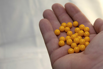 hand holding a handful of yellow pills