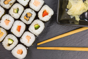 variations of maki sushi rolls with ginger and chopsticks