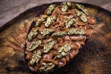 Chocolate egg with filling for Easter on wooden background.