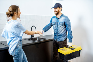 Handy man having a deal with young woman client after the repairment on the kitchen. Home repair...