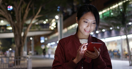 Woman check on cellphone in city at night