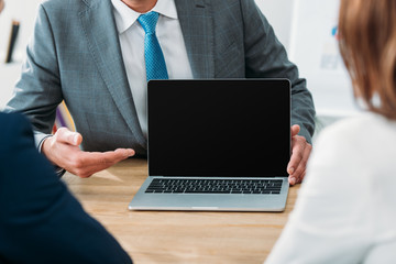 selective focus of advisor pointing with fingers at laptop with blank screen